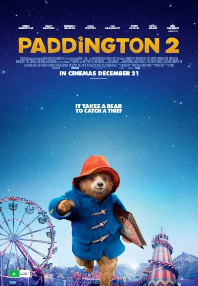 Cartel de Paddington 2 con el oso vestido de azul, sombrero rojo y un libro en la mano.